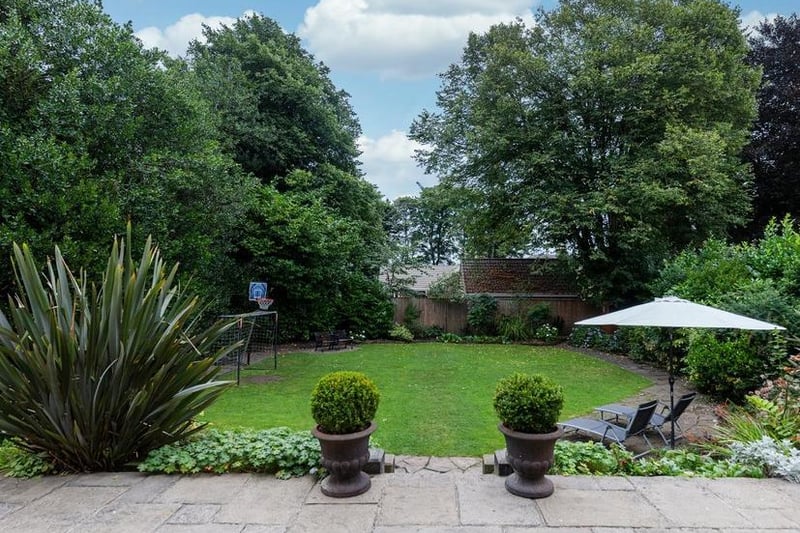 The attractive lawned garden is fringed with trees,  bushes and shrubs.