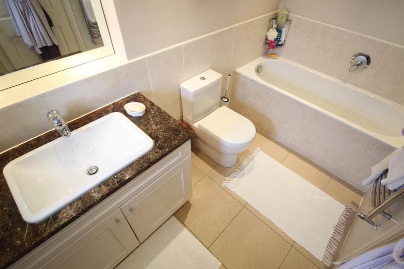 A modern bathroom suite includes a basin with a vanity unit surround.