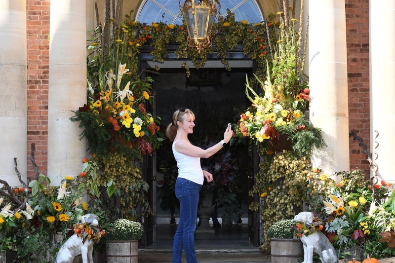 A visitor taking pictures of the floral art at the entrance to the house