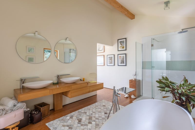 Sleek bathroom with a shower, a deep bath tub and side by side washbasins.