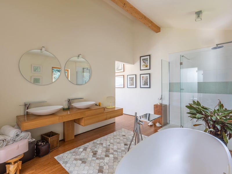 Sleek bathroom with a shower, a deep bath tub and side by side washbasins.
