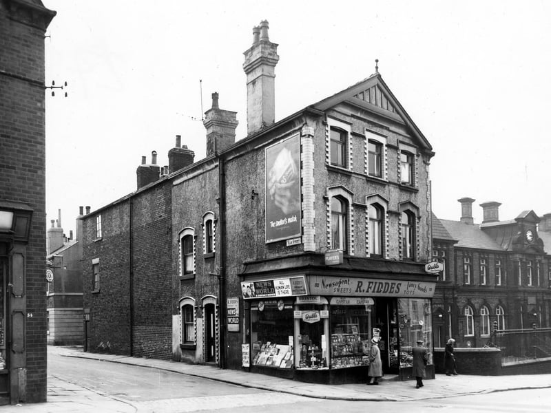 Beeston Road and the junction with Kiln Stree in July 1964.. A woman looks in the window of R. Fiddes, newsagents. To the far right is Hillside School, originally Beeston Hill Board School, a mixed school.