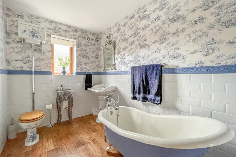 A blue and white bathroom with a deep, free standing bath tub.