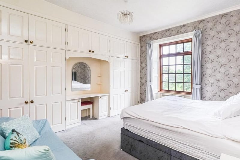 One wall is fitted with wardrobes and additional storage space in this bedroom.