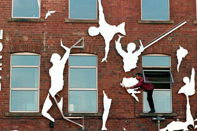 Sculptor Johnny White adds the finishing touches to his latest work on the wall outside Leeds Dance Centre .