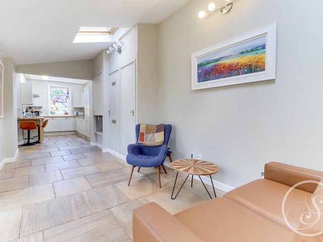 It also leads into a snug family area with a sofa and chair. The room benefits from underfloor heating, additional storage cupboards and double glazed folding doors leading onto the garden.