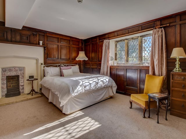 A huge fireplace and wood pannelling bring warmth to this bedroom within the property.