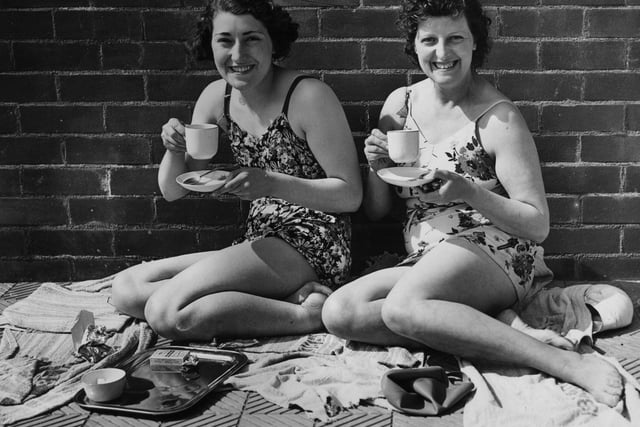 Two sunbathers enjoy a cup of tea in the sun at Bradford's new open air lido in May 1939 .