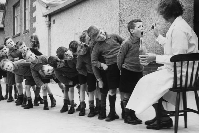 Children from Bradford lining up for a dose of medicine during a holiday at Morecambe. Year unknown.