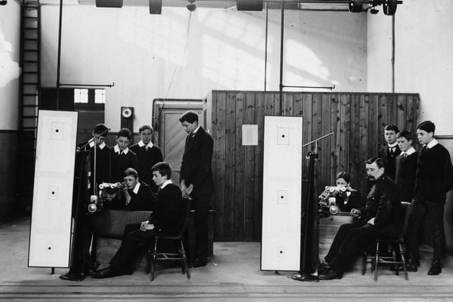 Schoolboys at Bradford College practise their marksmanship safely with the help of a rifle machine in February 1908.