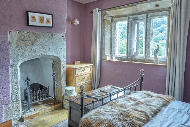 A stone fireplace and mullion windows are period features within this bedroom.