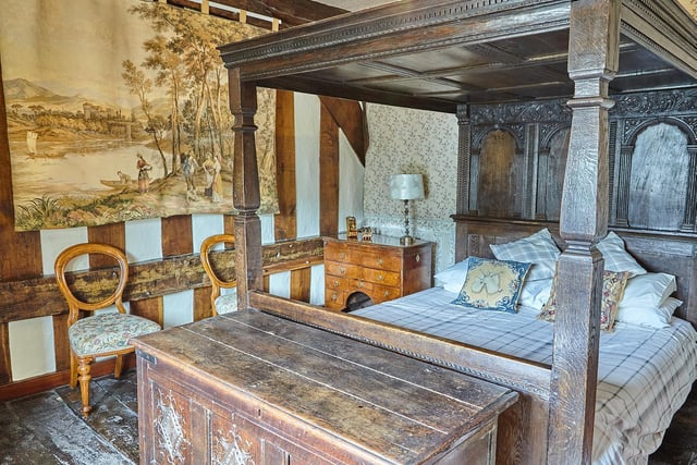 A carved four poster bed and wall tapestry add to the period feel of the house.