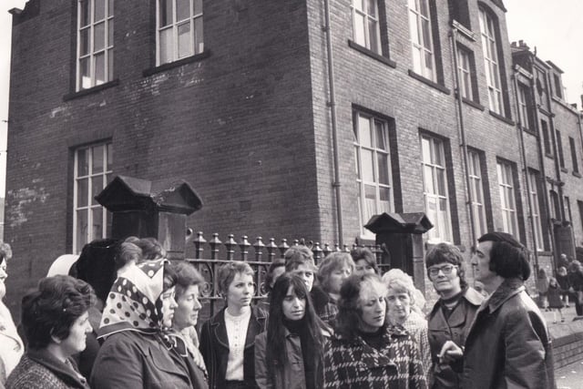 Edward Foster (right), vice chairman of Victoria Middle School Parent Teacher Association talks with other parents outside the gates of the school in April 1974.