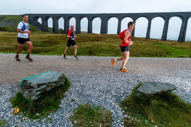Runners making their way alongside Ribblehead viaduct and onwards towards the summit of Whernside.