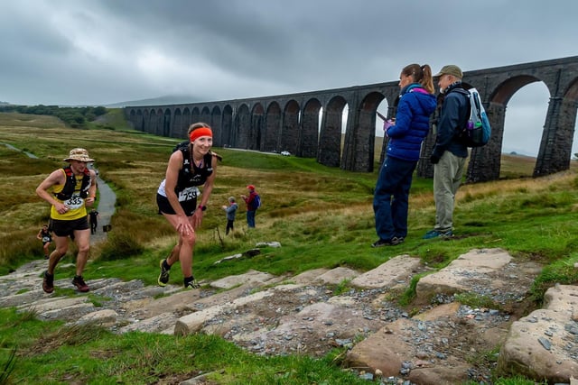 Runners making their way alongside Ribblehead viaduct and onwards towards the summit of Whernside.