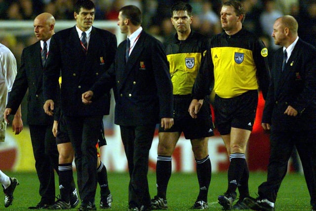 Referee Terje Hauge and a linesman are escorted from the pitch by security men at full-time.