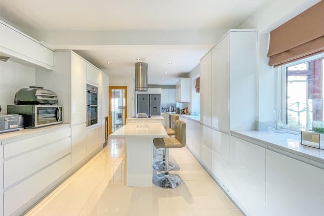High gloss units and granite surfaces feature in the high spec kitchen.