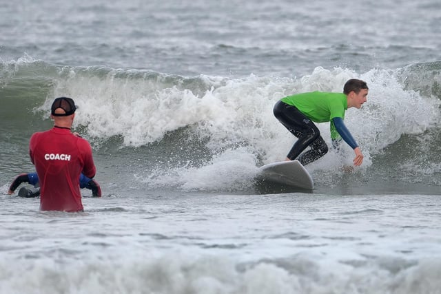 An instructor looks on as surfers take on the waves.