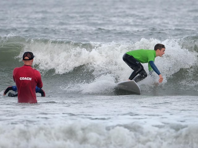 An instructor looks on as surfers take on the waves.