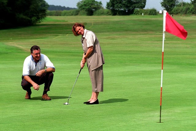 Jill Howarth, of Macmillan Cancer Relief, lines up a shot on the green at Garforth Golf Club with the help of club captain John Macmillan during a charity fundraising event in July 1997.