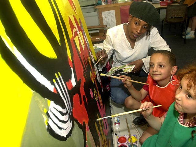 Artist Marcia Brown helps Beeston Primary School pupils Harry Loucas and Georgina Brayshaw with a painting the children were producing in July 2003.