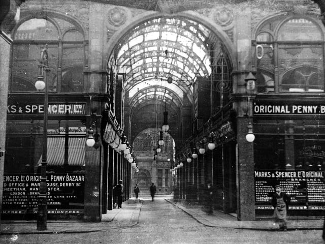 A view down Cross Arcade showing, elaborate roof and street lights, with Marks & Spencer on either side. This photograph shows the first shop occupied by the 'Original Penny Bazaar' out-side the market, where it operated from 1904.