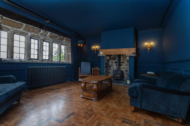 A wooden floor, mullion windows and rustic fireplace give this room strong character.