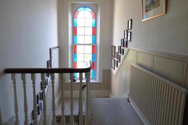 The staircase and feature arch window with stained glass.