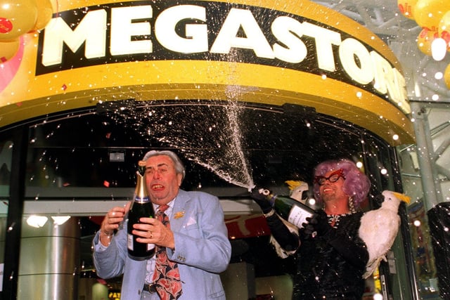 Actor Barry Humphries struggles to open his bottle of champagne as Dame Edna Everidge, a disguised Richard Branson, is spraying bubbles to open the Virgin Megastore..