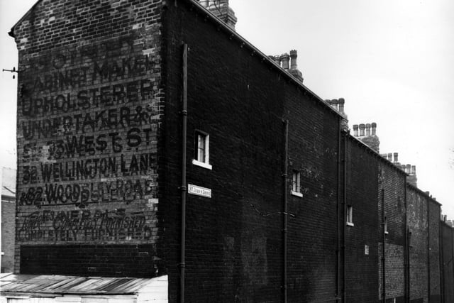 The gable end wall of Woodsley View with a faded wall sign advertising a joinery and funeral directors business pictured in November 1963.
