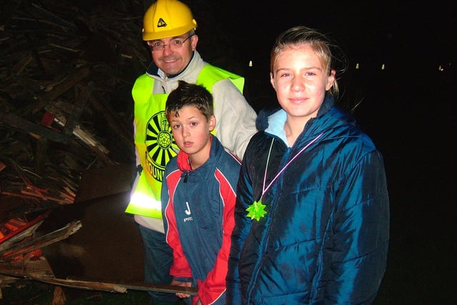 Crowlees Junior School pupils Josh Dyson and Edan Walker, from year six, lighting the bonfire with Mirfield Round Table's Robert Cole in 2005