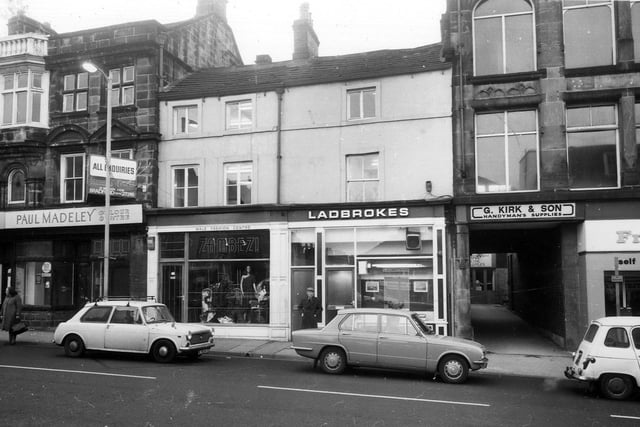 The west side of Kirkgate. Just visible on the right is Freeman Hardy Willis footwear. Next to this is the entrance to a yard which contains G. Kirk & Son, handyman's supplies. Continuing left is Ladbrokes Betting Office and Zambezi ladies' and menswear.