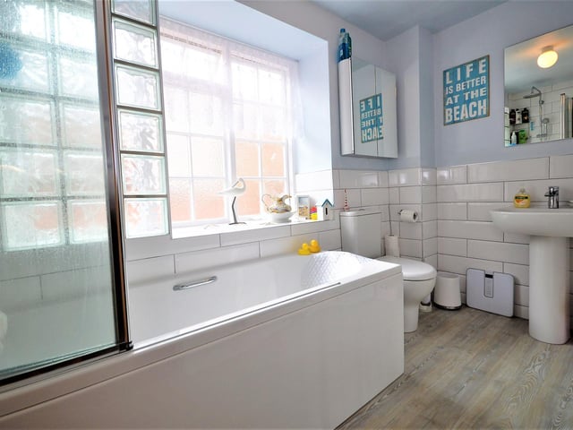 A bath with shower, and plenty of floor space in the bathroom.