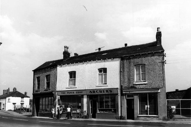 Main Street in East Ardsley pictured in July 1975 showing Archer's 'the paper shop'  in the centre, outside which a group of children are standing.