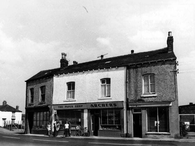 Main Street pictured in July 1975 showing Archer's 'the paper shop'  in the centre, outside which a group of children are standing.