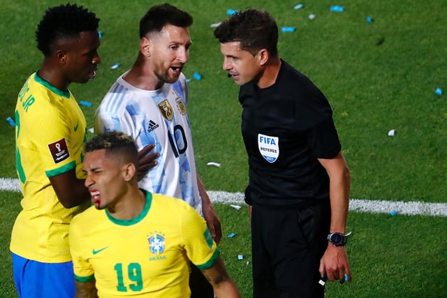 The blood on Raphinha is clear as Brazil team mate Vinicius Jr, left, and Argentina superstar Lionel Messi, centre, talk to referee Andrés Cunha.
