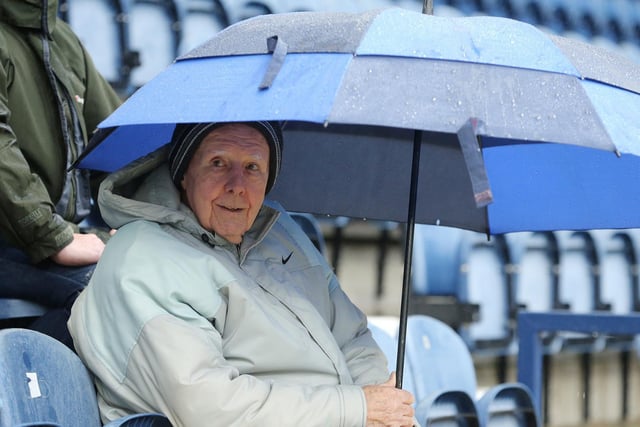 A PNE fan shelters from the rain at Deepdale