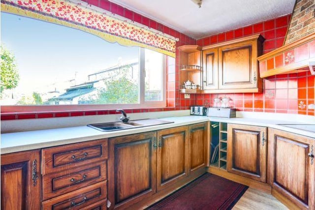 Through this room is the kitchen, which also benefits from a large window overlooking the garden. Its red kitchen tiles and units may need updating.