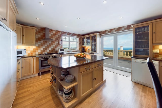 A spacious kitchen has a central island unit, and patio doors that lead out to the sun terrace.