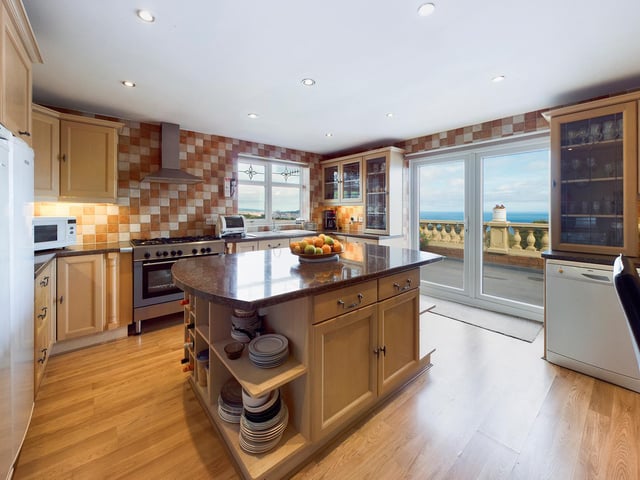 A spacious kitchen has a central island unit, and patio doors that lead out to the sun terrace.