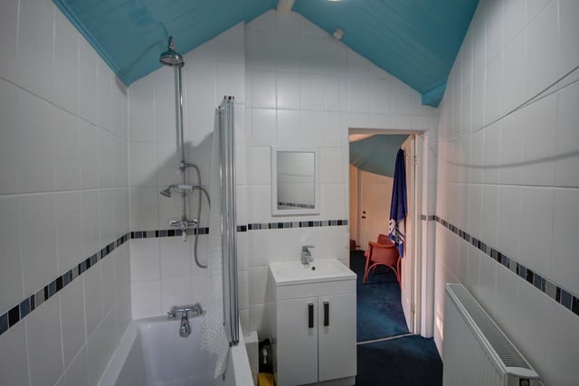 The white tiled bathroom includes both bath and attached overhead shower.