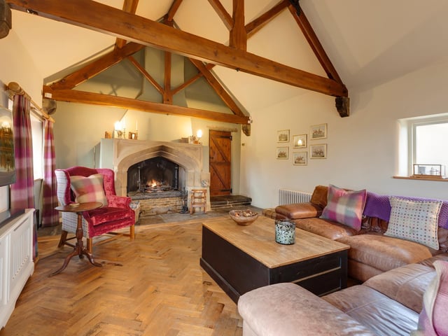 A stunning feature fireplace and vaulted ceiling bring great warmth and character to this room within Sycamore Farm, Derbyshire.