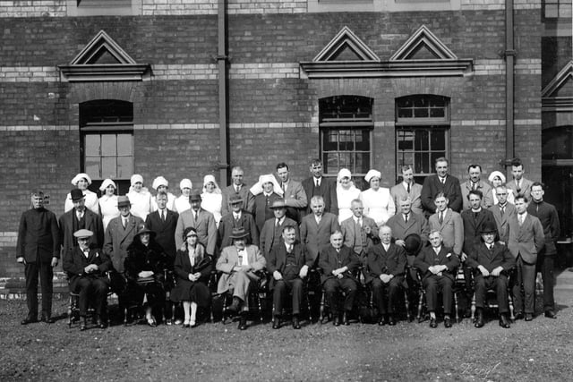 A formal group photograph showing staff and officials of a hospital, on a lawned area outside the building.On the back of the photograph is written in pencil, "Cookridge Hospital, Leeds 1920s/30s?" Leodis say having looked at other images, that it isn't Cookridge, and there is a possibility that it's not Leeds at all!