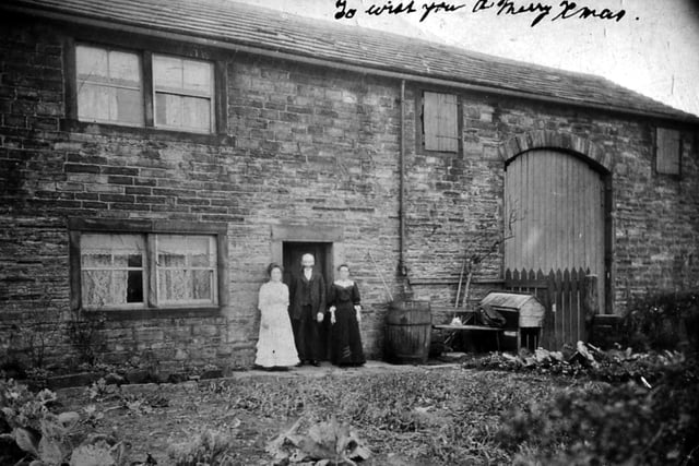 An undated view of an unidentified man and two women posing for the camera outside what appears to be a stone-built two-story farmhouse with attached barn. They are wearing a late nineteenth/early twentieth century style of dress. It was originally described as Howley Hall Farm but this is not now thought to be the case.