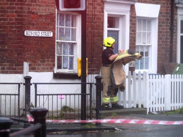 A firefighter preparing on Bedford Street with the danger of falling debris from nearby properties.