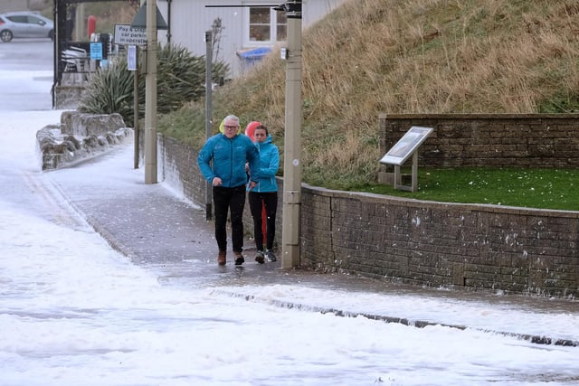 Residents caught out in the stormy weather run to avoid the incoming waves and foam.