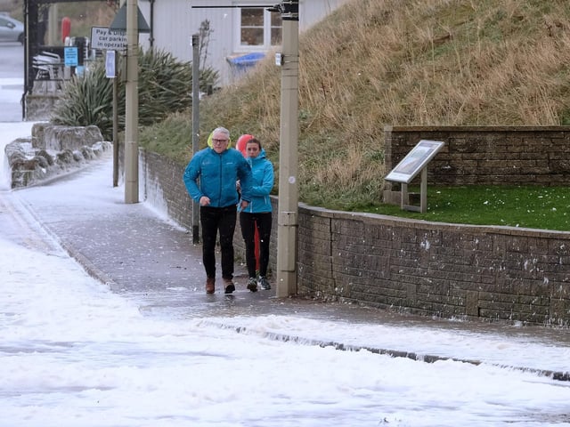 Residents caught out in the stormy weather run to avoid the incoming waves and foam.