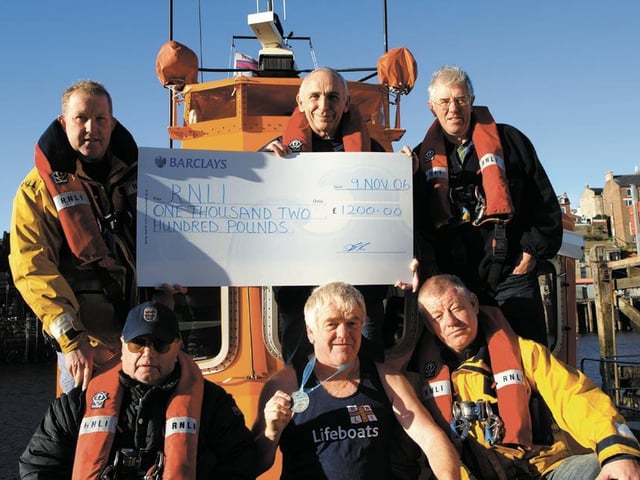 Runner Dennis Booth presents a cheque to the Whitby lifeboat crew.
