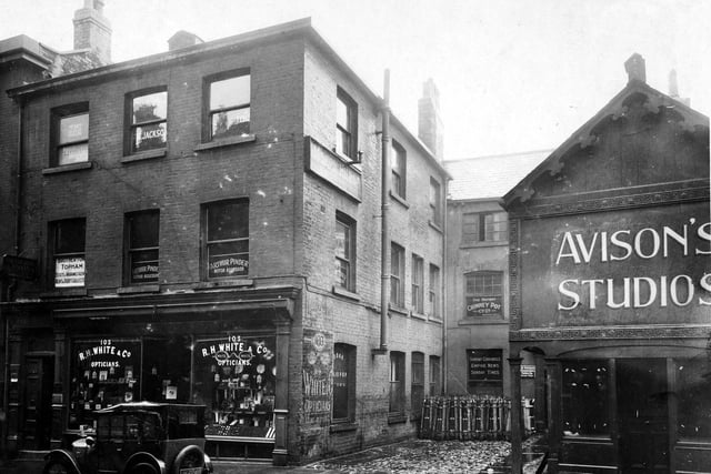 Albion Street in July 1927. Pictured are R.H. White, opticians. Upper floors occupied by various companies, logos on window for 'Brotherton Topham Estates and Insurance Agent, Rent and Debt collectors', 'Arthur Pinder, Motor Assessor'.