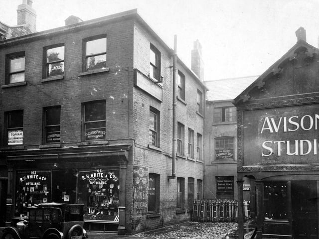 Albion Street in July 1927. Pictured are R.H. White, opticians. Upper floors occupied by various companies, logos on window for 'Brotherton Topham Estates and Insurance Agent, Rent and Debt collectors', 'Arthur Pinder, Motor Assessor'.